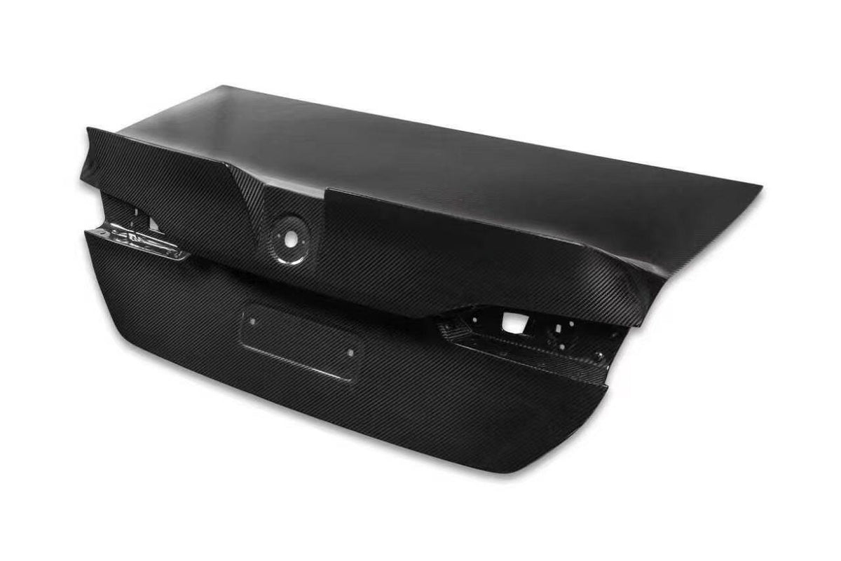 A black carbon fiber rear trunk lid cover for a BMW 5 Series (G60/G68), shown from a three-quarters angle.